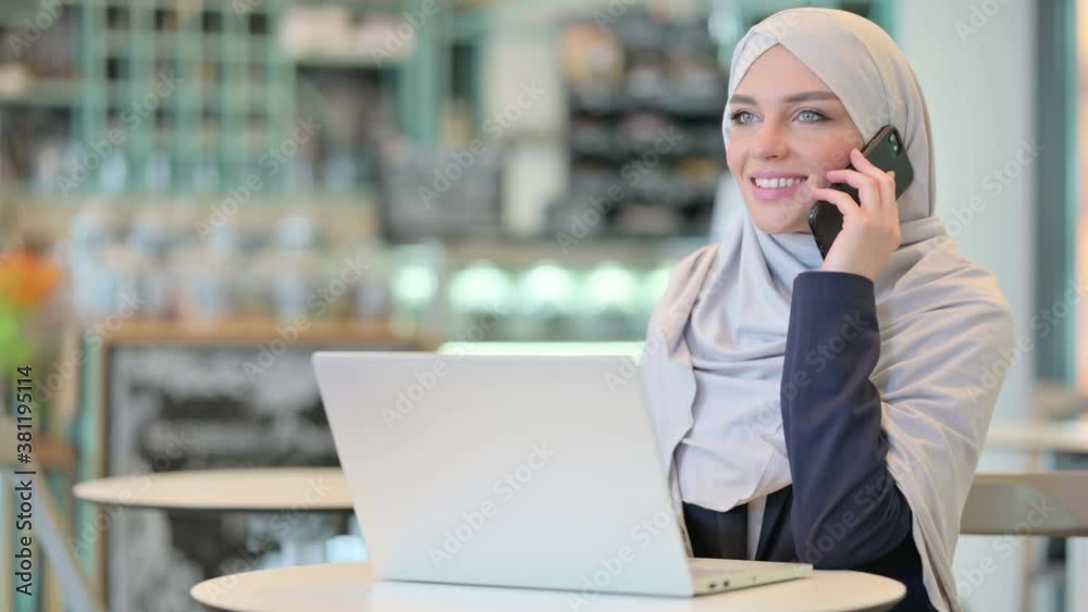 Young Arab Woman with Laptop Talking on Smartphone Young Arab Woman with Laptop Talking on Smartphone