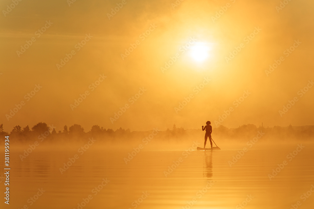 Sportsman rowing with paddle board during sunrise