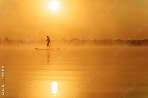 Young man using paddle board for swimming at lake