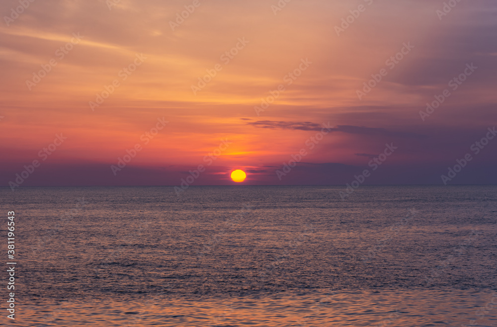 Beautiful orange sunset over the sea. The sun sets on the horizon. Relaxing sea landscape. Purple shades of sky and sea water. Sunset over the Black sea. The natural background.