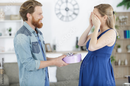 man surprising a pregnant woman with a gift
