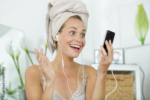 young beautiful lady with towel happily listening to her music photo