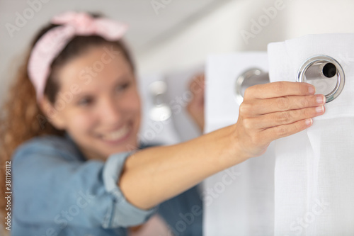 young woman installing curtains over window
