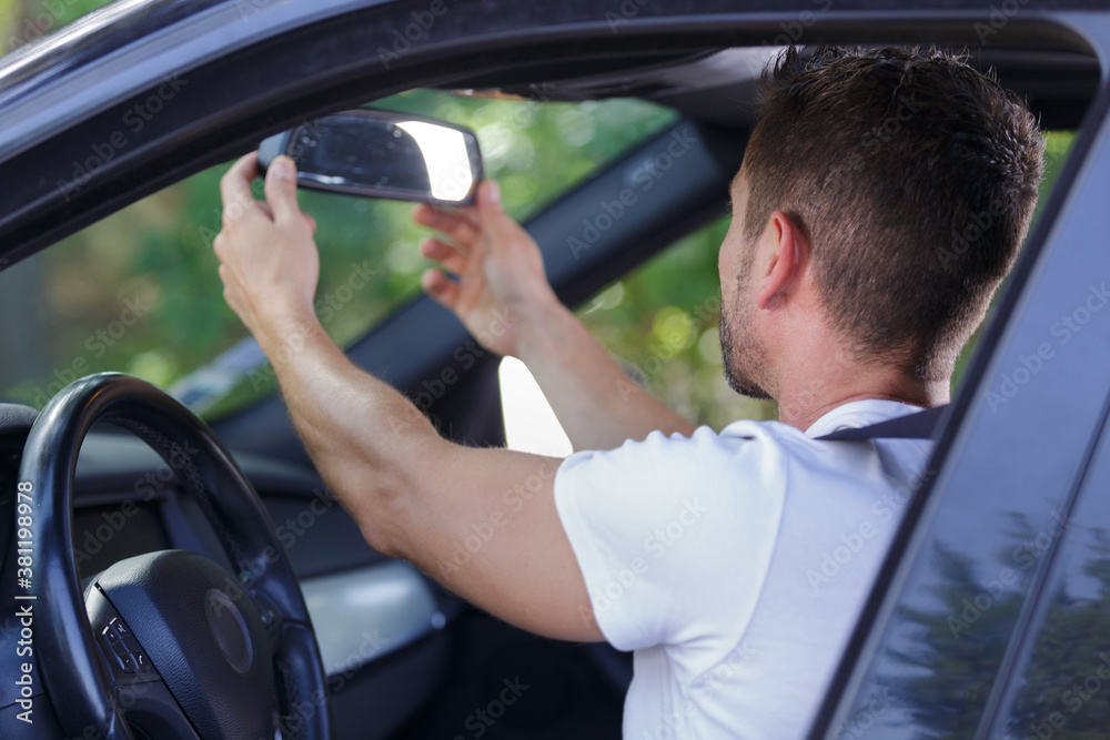 man adjusting the rearview mirror in his car before driving man adjusting the rearview mirror in his car before driving