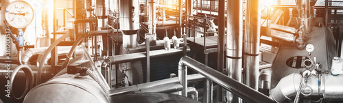 Modern industrial gas boiler room equiped for heating process with heating gas boilers, pipe lines, valves. Panoramic view, composed mixed media. Back sun flare.