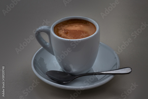Fototapeta Naklejka Na Ścianę i Meble -  Delicious coffee in a white porcelain cup, with saucer and teaspoon