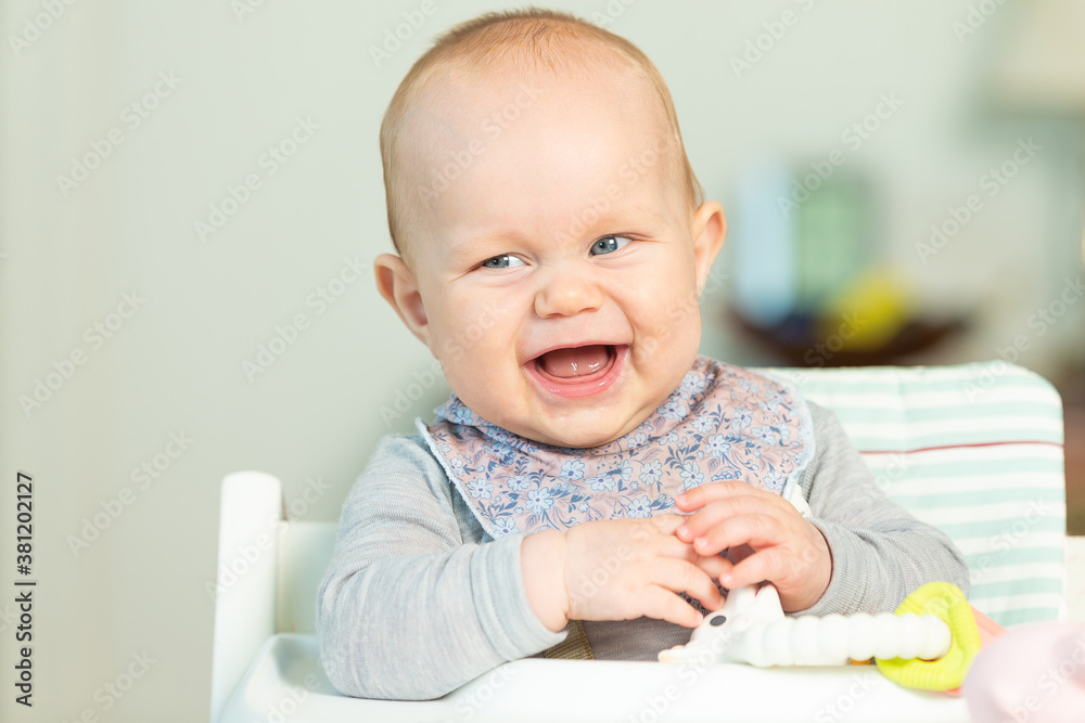 Happy 6 months old child playing in high chair. Happy 6 months old child playing in high chair.