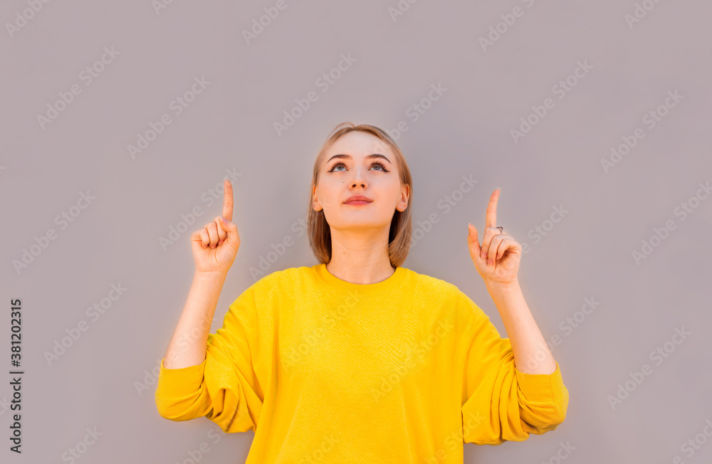 Happy woman pointing up with both hands isolated on a gray background Happy woman pointing up with both hands isolated on a gray background