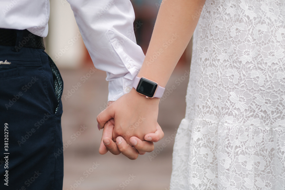 Back view of groom and bride hold hands. Close of on hand male and female