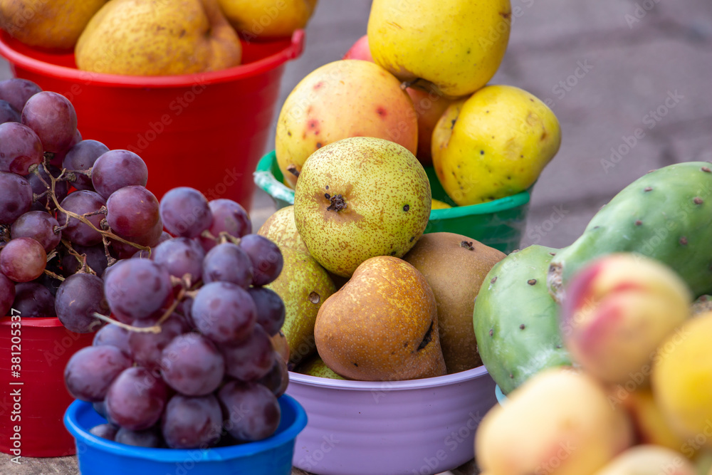 Fruta orgánica en baldes de colores, peras, uvas, duraznos, tunas, rambután.