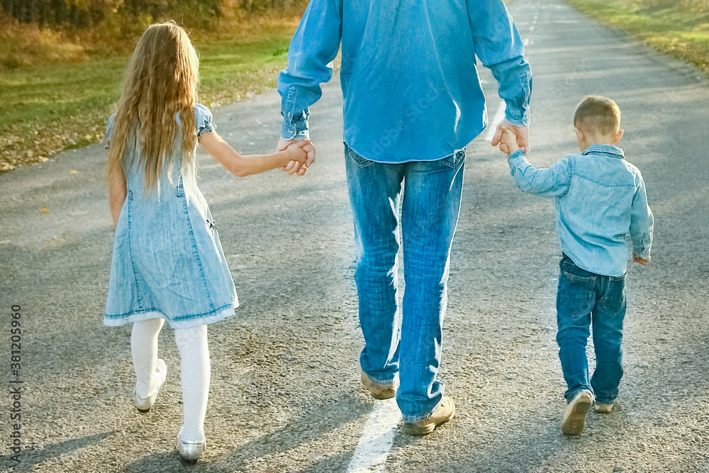 A Happy parent with child are walking along the road in the park on nature travel A Happy parent with child are walking along the road in the park on nature travel