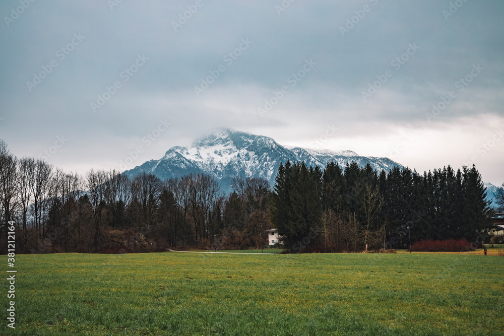 outskirts Europe village in Austria moody environment outdoor space in November rainy gray day time with small houses and Alp mountain in snow and smoke background scenic view soft ficjs photo
