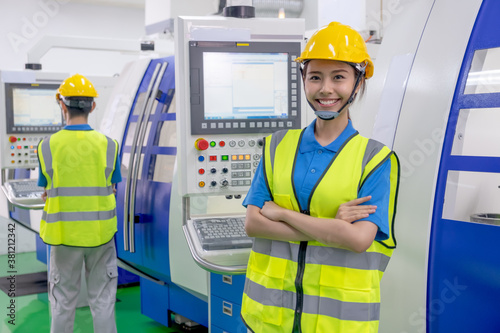 Factory worker woman with uniform stand with cross arm and smile look to camera. Concept of good management support system help employee in industrial business work with happiness in workplace.