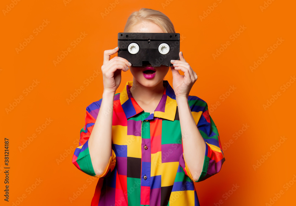 Style blonde in 90s clothes with VHS cassette - obrazy, fototapety, plakaty 