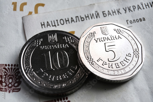 Ukrainian hryvnia coins placed on 100 UAH bills. New type of coins released in 2019 substitute paper notes. Words in Ukrainian translated 