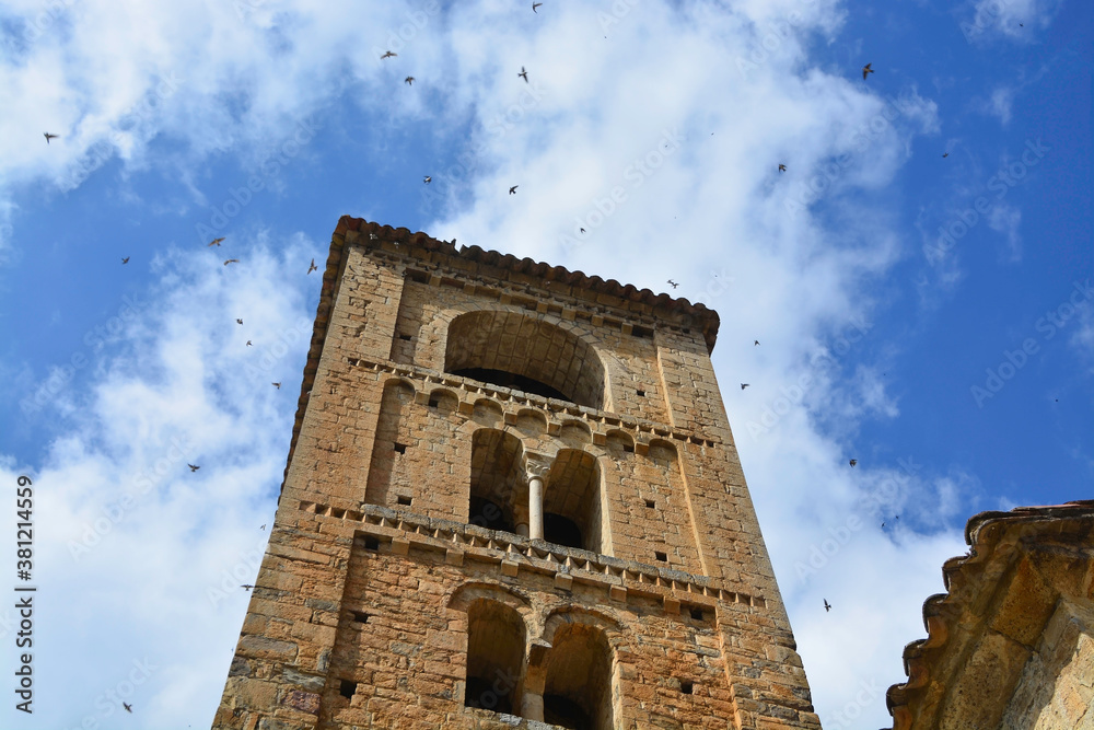 BEGET, CATALONIA, SPAIN, EUROPE, SEPTEMBER 2020. Beautiful tower of the Romanesque church of San Cristóbal surrounded by birds in the beautiful medieval town of Beget.