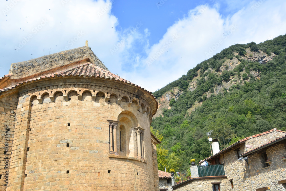 BEGET, CATALONIA, SPAIN, EUROPE, SEPTEMBER 2020. Fantastic Romanesque church of San Cristóbal with a window in the rear vault and surrounded by stone houses in the beautiful medieval town of Beget