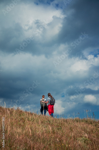 highland dramatic mountain sky vertical picture wallpaper poster photography with hiking couple back to camera active life style concept with empty copy space for your text