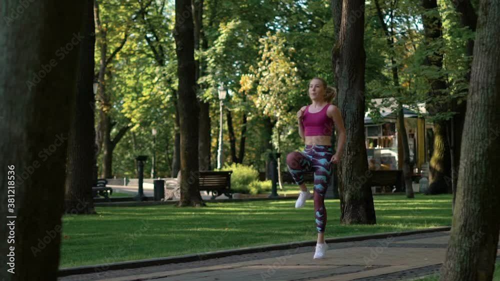 fit athletic cute blonde european girl doing exercises for the buttocks in the park. The girl is jumping. Cardio exercise. FullHD slowmotion fit athletic cute blonde european girl doing exercises for the buttocks in the park. The girl is jumping. Cardio exercise. FullHD slowmotion