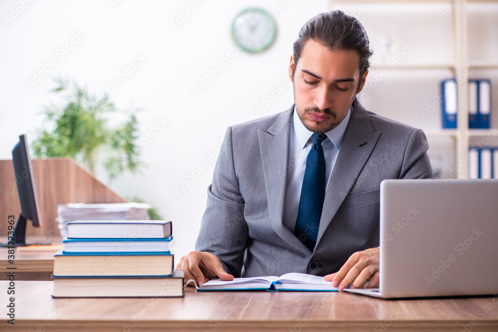 Young male businessman reading books at workplace Young male businessman reading books at workplace