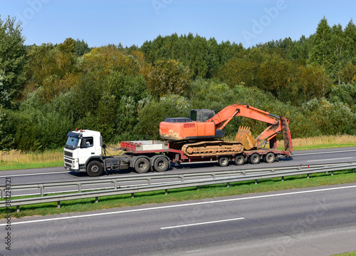 фотографія Trailer truck with long platform transport the Excavator on highway