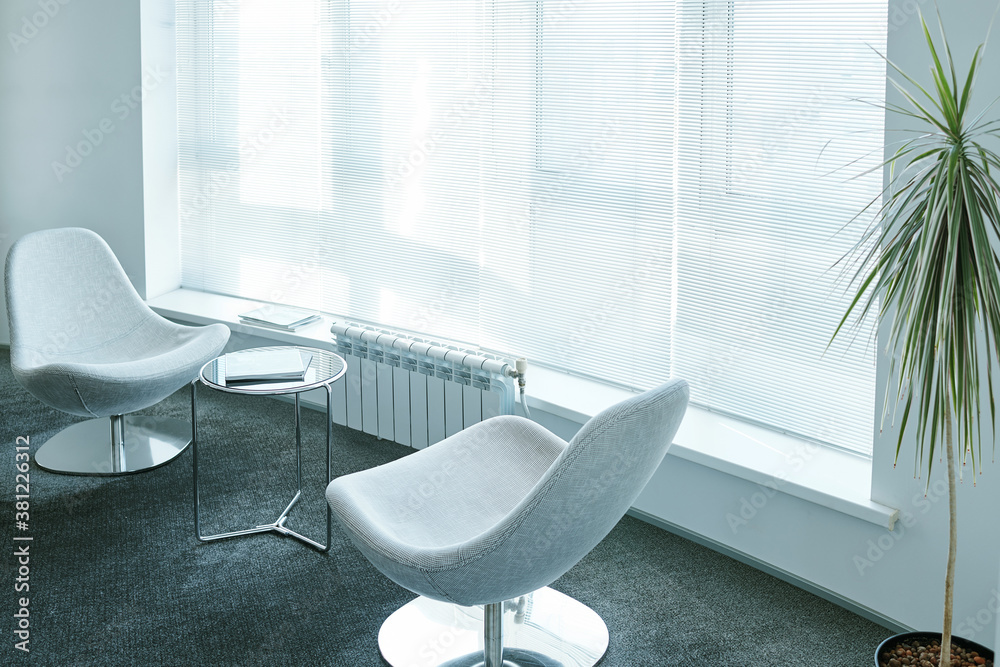 Two comfortable armchairs surrounding small round table with business documents Two comfortable armchairs surrounding small round table with business documents