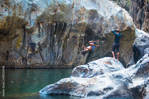 Somoto Canyon, Nicaragua. Two young man enjoying the natural scenery, jumping into the calm waters. Rocky mountains surroundings. Beautiful dry summer landscape, Central America. photo
