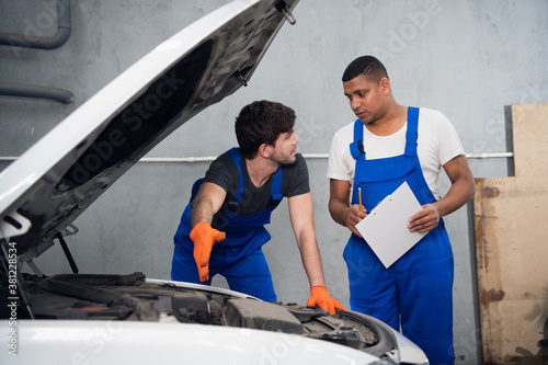 Workman consults with a colleague about a car repair