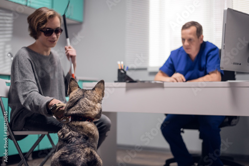 A blind person with a guide dog having an appointment at a vet clinic. photo
