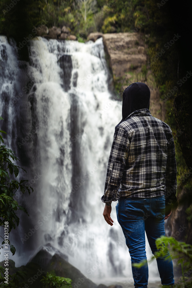 Obraz premium Solo man discovering waterfall in middle of forest. Inspirational and travel concept