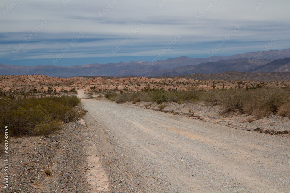 Road trip. Traveling along the dirt road across the arid desert, canyon and mountains. 