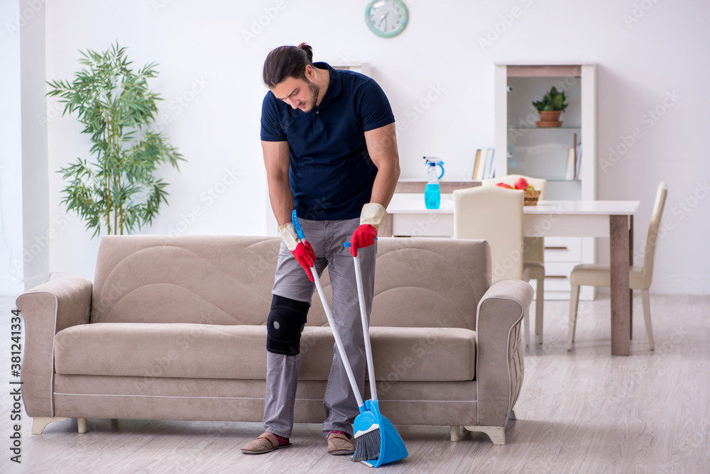 Young leg injured contractor cleaning the house Young leg injured contractor cleaning the house