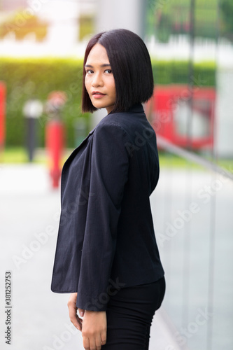Fashion portrait of young beautiful woman sexy outdoor. black suit, standing on blur urban background.