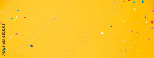 Colorful confetti on yellow banner background with copy space in the middle photo