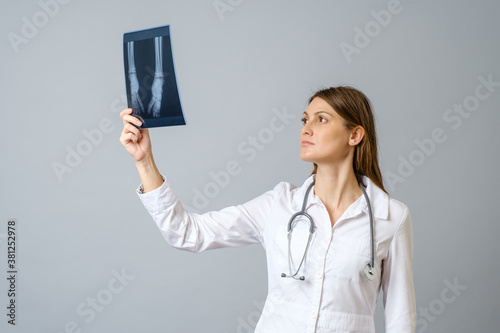 Female doctor examining x-ray image of legs of newborn baby photo
