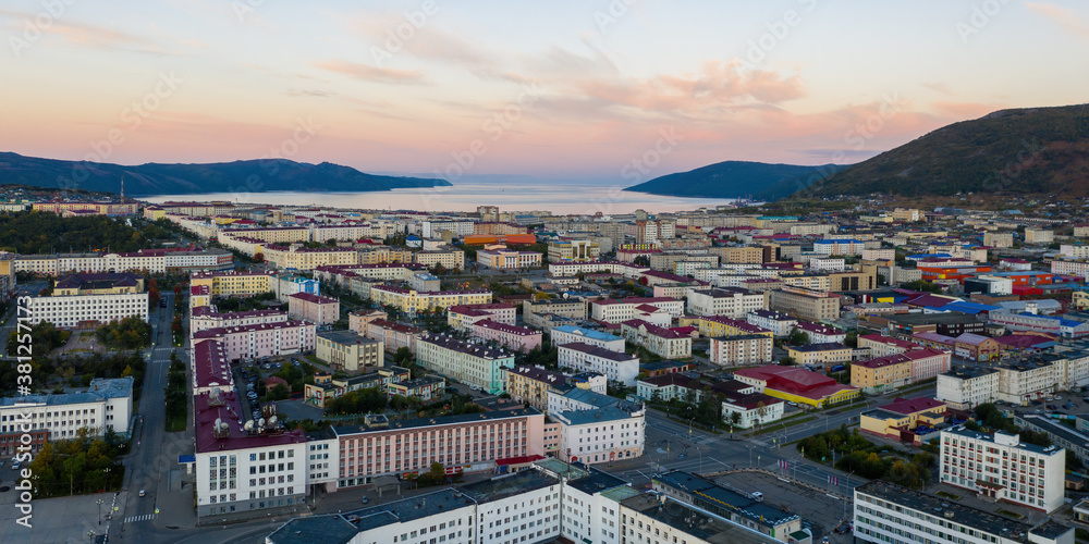 Panorama of the city of Magadan. Beautiful morning cityscape. Aerial view of buildings and streets. In the distance there are mountains and a sea bay. Magadan, Magadan Region, Far East Russia. Siberia