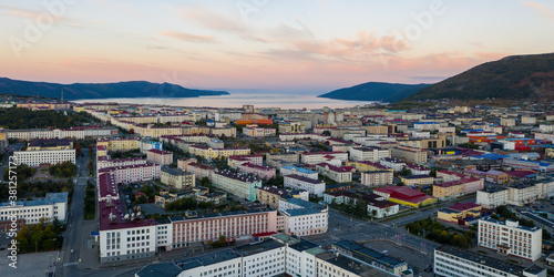 Panorama of the city of Magadan. Beautiful morning cityscape. Aerial view of buildings and streets. In the distance there are mountains and a sea bay. Magadan, Magadan Region, Far East Russia. Siberia