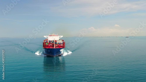 A large container ship for transporting goods near the port of Singapore. A container ship carries cargo across the ocean. Transportation. Delivery. Logistics. Aerial 4K shot.