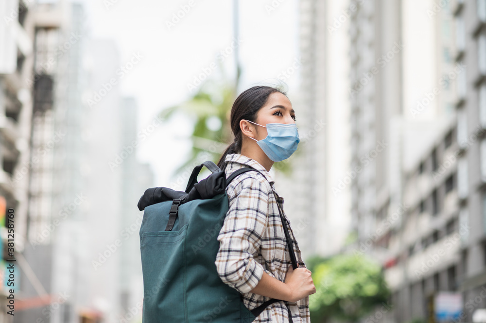 New normal of traveler. Side view of Alone young asian beautiful woman travel in holiday with backpack and wearing protection mask virus for safety trip. She walking alone in the city. New normal of traveler. Side view of Alone young asian beautiful woman travel in holiday with backpack and wearing protection mask virus for safety trip. She walking alone in the city.