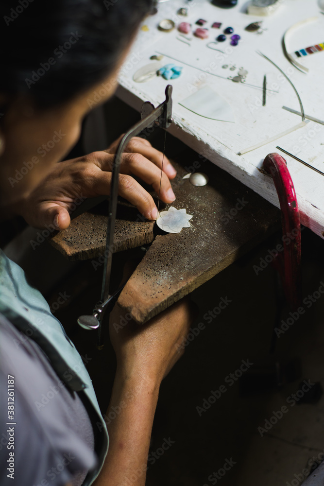Obraz premium Jewelry maker cutting metal with a band saw in the workshop. Professional jewelry jeweler on your workbench.