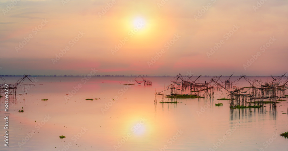 scenery of sunrise over lake with thai traditional fishing trap at Pakpra