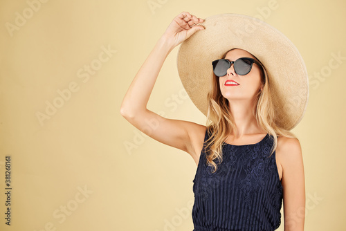 Portrait of stylish fashionable young woman in straw hat and sunglasses looking up