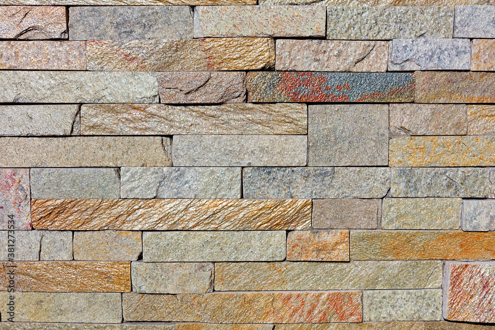 The texture of the old wall lined with shiny rough sandstone tiles. The texture of the old wall lined with shiny rough sandstone tiles.