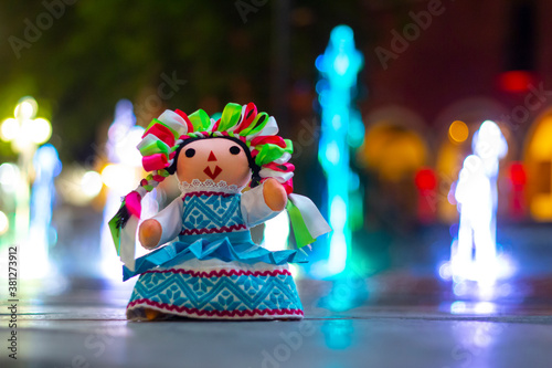 Muñeca de trapo tradicional mexicana, fondo con chorros de agua de colores