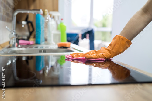 Female hand cleaning modern glass ceramic electric surface with a sponge in her kitchen