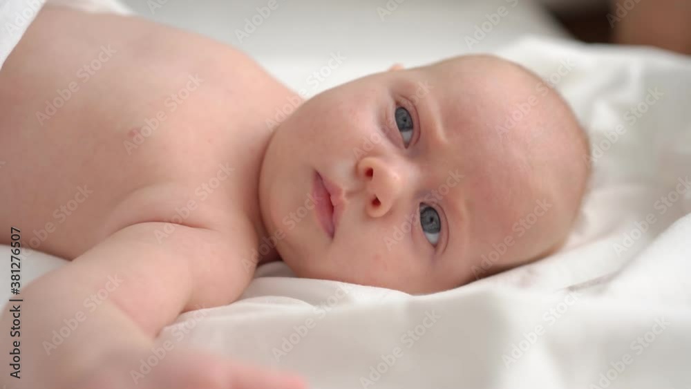 cute red-haired baby lies on a white bed. cute red-haired baby lies on a white bed.