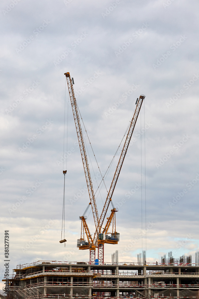 Building under construction and tower cranes against the sky
