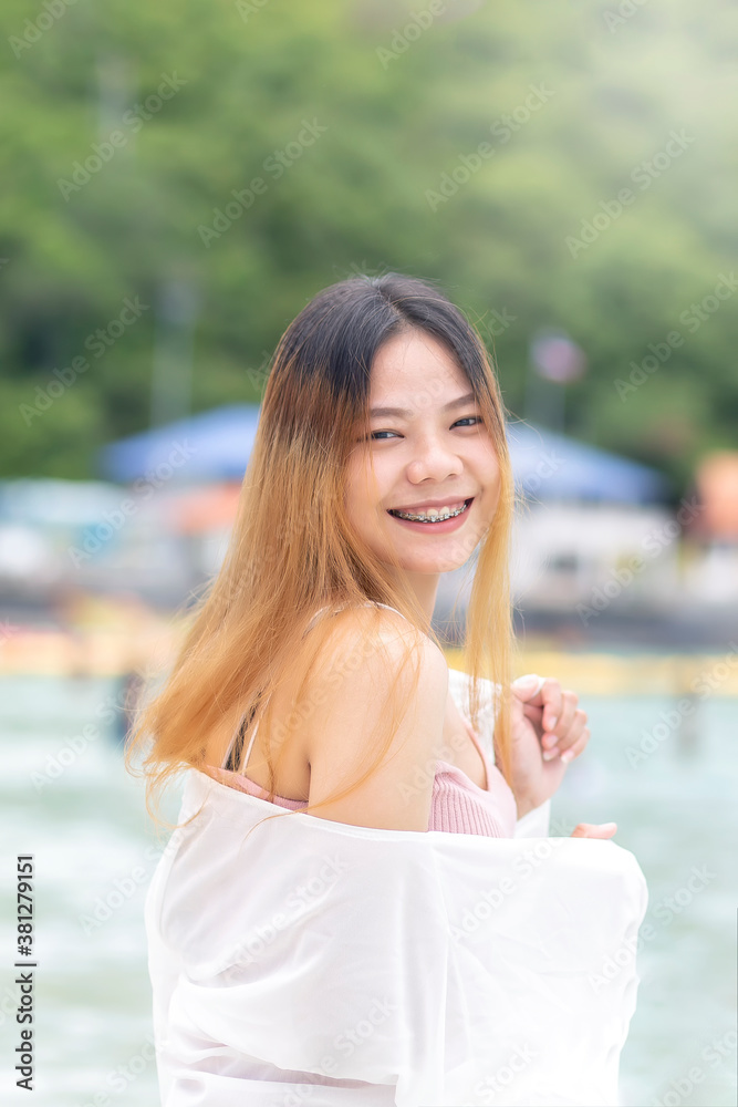 Beautiful Asian women smiling on the beach against the mountain background. Asian women strolling along the beach for a vacation. Beautiful Asian women smiling on the beach against the mountain background. Asian women strolling along the beach for a vacation.