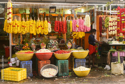 Flower shop in the street during Onam festival in Kerala, India. Baskets full of colorful flowers, garland for sale in shop on a street. Many yellow garland of marigold, Jasmine displayed. photo