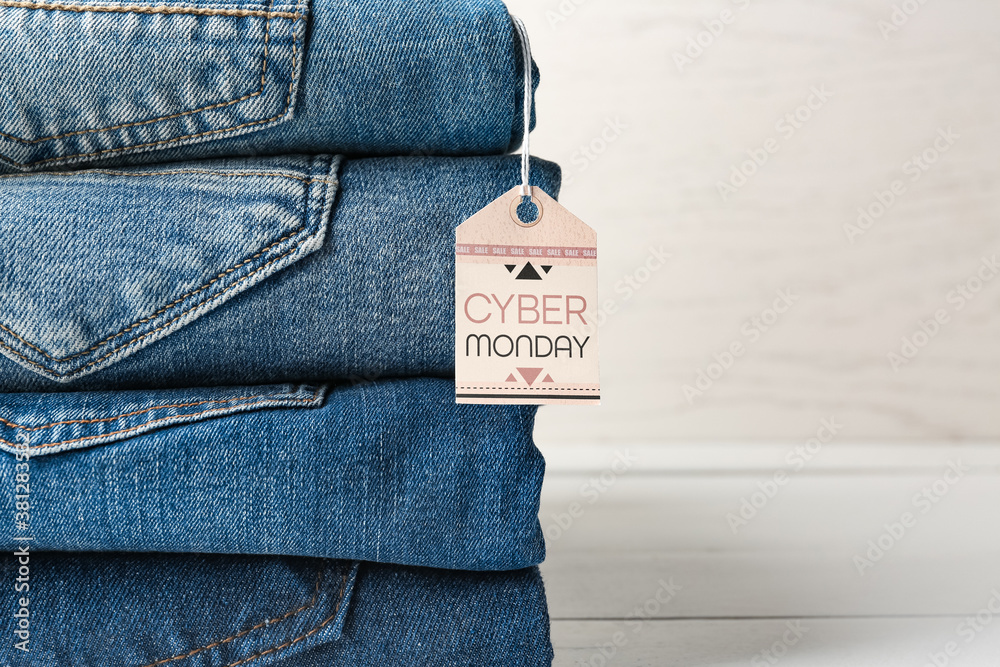 Stack of jeans clothes and tag with text CYBER MONDAY on table, closeup  Stock Photo | Adobe Stock